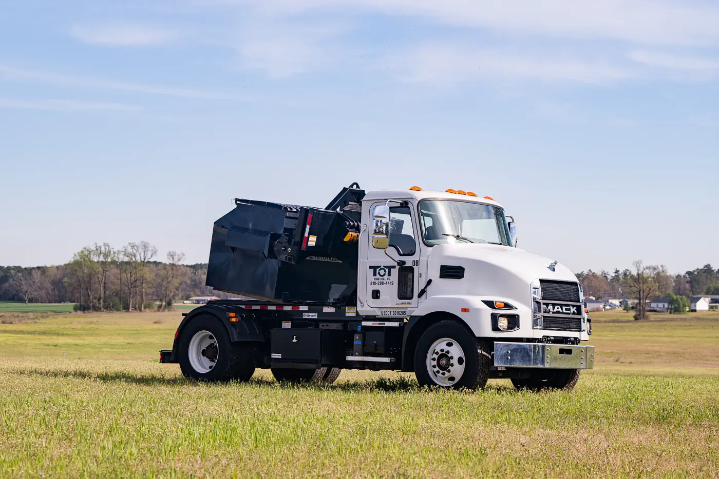 Tons of Trash front-end loader truck delivering a commercial dumpster