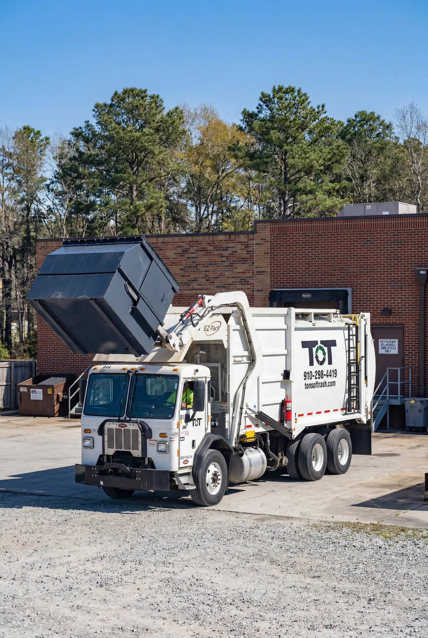Tons of Trash front-end loader truck emptying a commercial dumpster