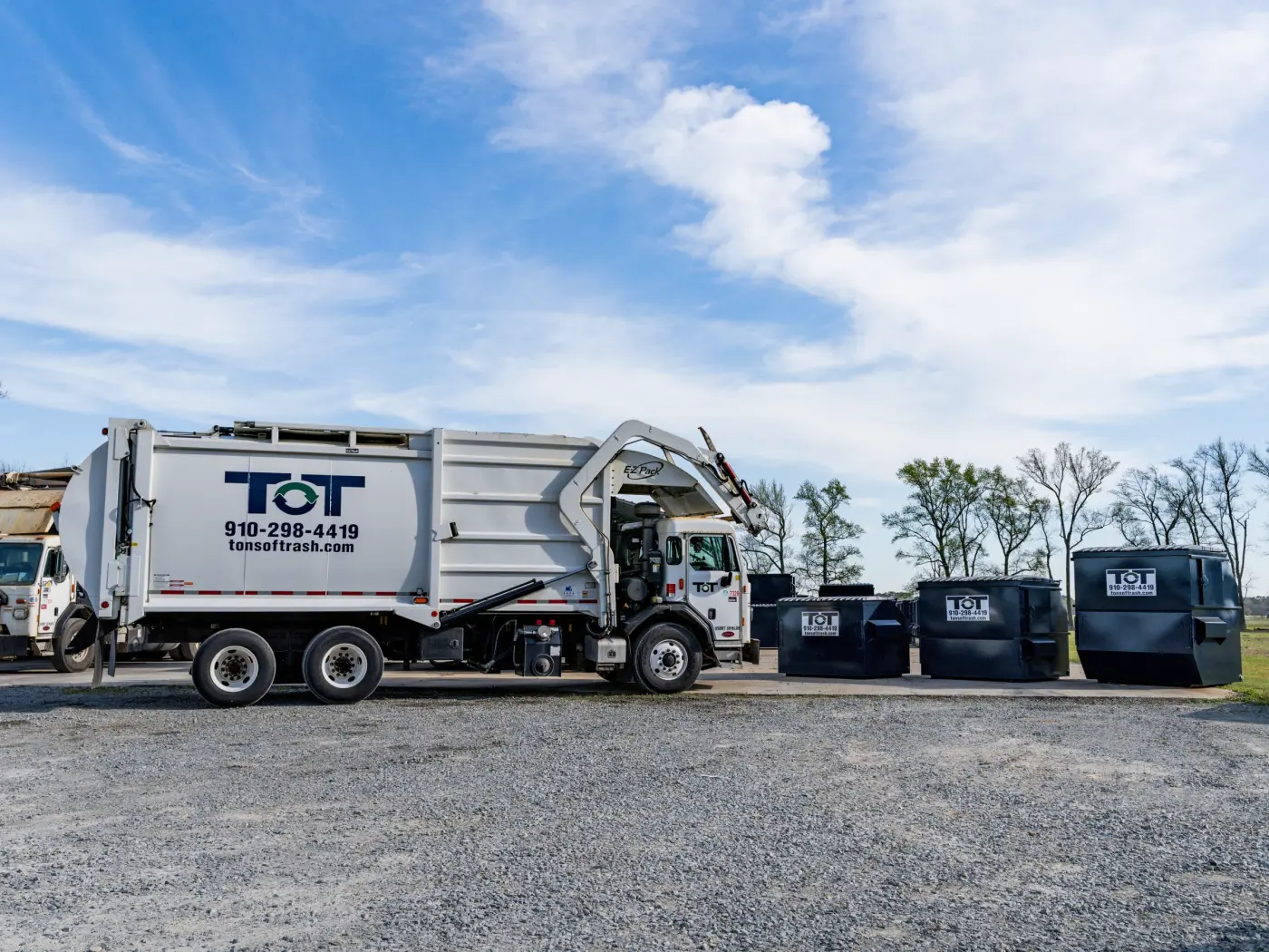 Tons of Trash front-end loader truck emptying a commercial dumpster