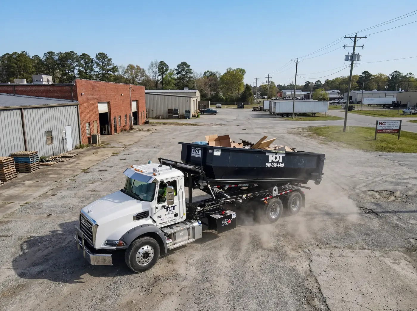 Tons of Trash roll-off truck delivering a dumpster